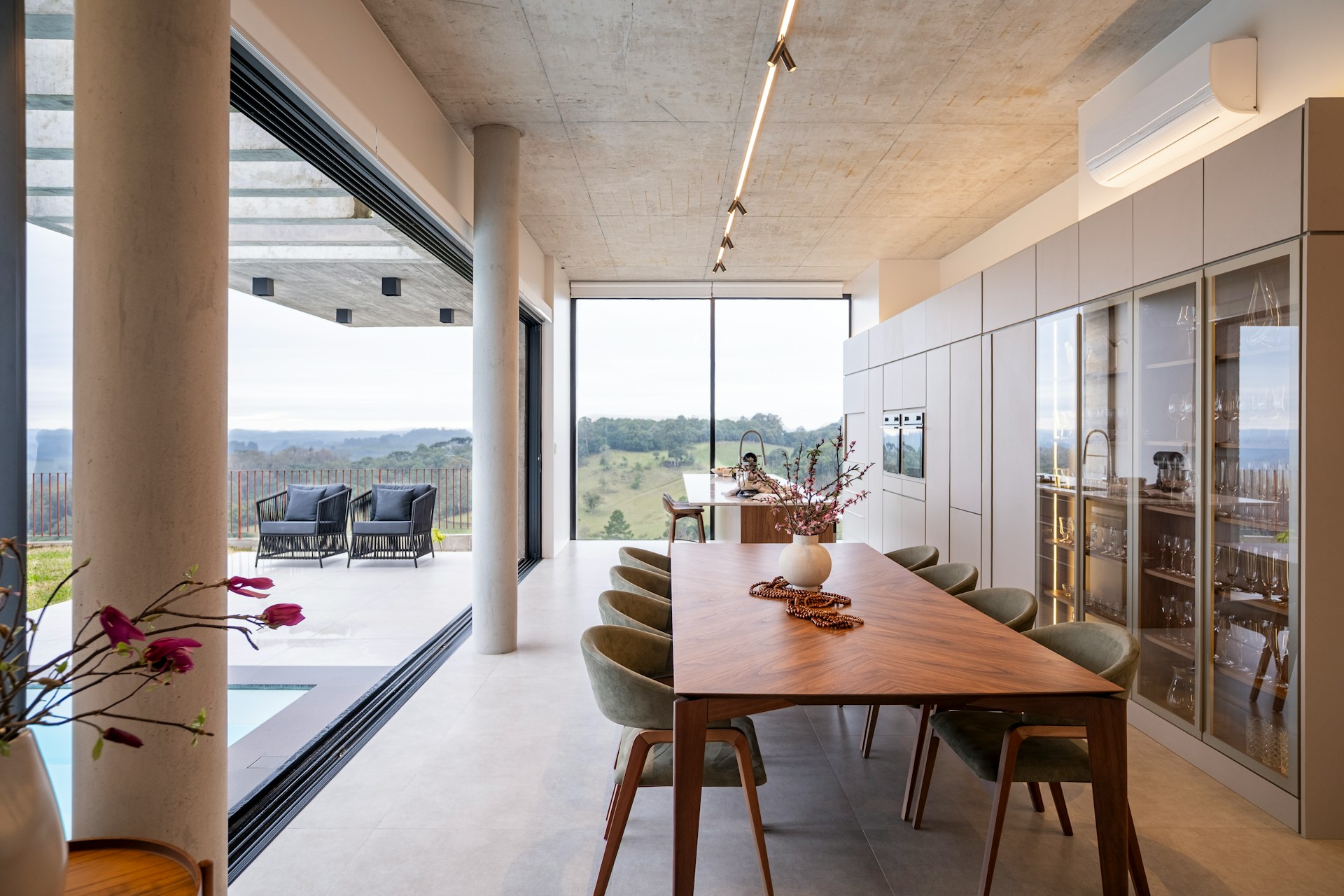 Salle à manger moderne avec de larges baies vitrées et une vue panoramique.